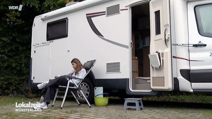 Jülide Toktamis sitzt vor ihrem Wohnmobil auf einem Campingstuhl. 