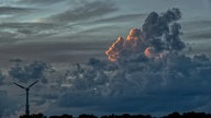 Ein bewölkter Abendhimmel  mit einem Windrad