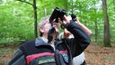 Lutz Falkenried und Heiner Heile blicken mit Ferngläsern in die Baumkronen
