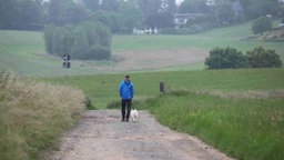 Ein Mann geht bei trübem Wetter mit einem Hund über einen Feldweg spazieren