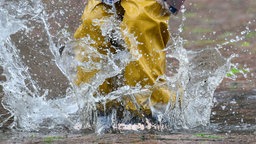 Mensch mit Regenhose springt in Pfütze