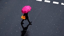 Frau mit Regenschirm auf einer Straße