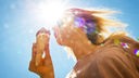 Eine Frau genießt bei Temperaturen über 30 Grad Celsius ein Eis in der Sonne. 