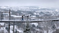 Spaziergänger gehen über den Skywalk neben der Bobbahn in Winterberg