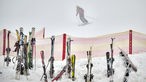 Skier stecken vor einer Skipiste im Schnee
