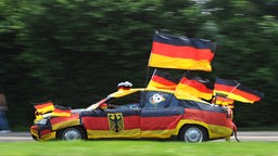 Fußballfan fährt mit seinem mit WM-Artikeln geschmückten Auto 