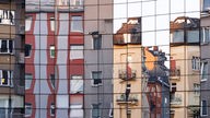 Wohnhäuser in der Kölner Innenstadt spiegeln sich in einer Glasfassade