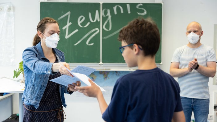  Ein Schüler der Klasse 5b der Gesamtschule Münster Mitte erhält sein Zeugnis aus den Händen der Lehrerin Kathrin Weiß.