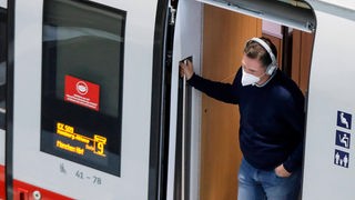 Ein Fahrgast mit FFP2 Maske steht im Eingang eines ICE Zug