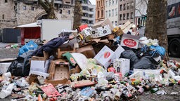 17.02.2023, Nordrhein-Westfalen, Köln: Zusammengefegter Müll aus der Weiberfastnacht liegt auf der Straße