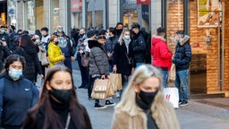 Das Bild zeigt Menschen mit Maske in einer Fußgängerzone.