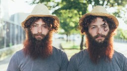 Zwei Zwillingsbrüder mit gleichem Hut, T-Shirt und Frisur