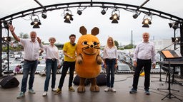 Die Maus, Moderator André Gatzke und Mitglieder des WDR Rundfunkchores stehen gemeinsam auf der Bühne im Autokino