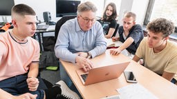 Fünf junge Männer sitzen vor Laptops und arbeiten an einem Notenschreibprogramm.