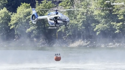 Hubschrauber tankt Wasser aus einem See