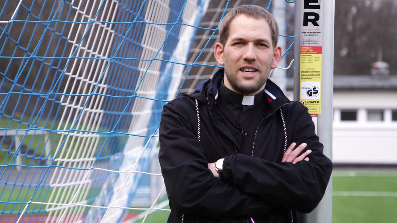 Patrick Kaesberg steht mit Priesterkleidung im Fußballtor