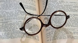 Brille liegt auf aufgeschlagenem Buch