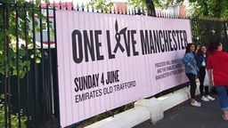Fans stehen in Manchester vor einem "One Love Manchester"-Banner. 