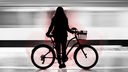 Eine Frau steht mit ihrem Fahrrad an einer U-Bahn-Haltestelle.