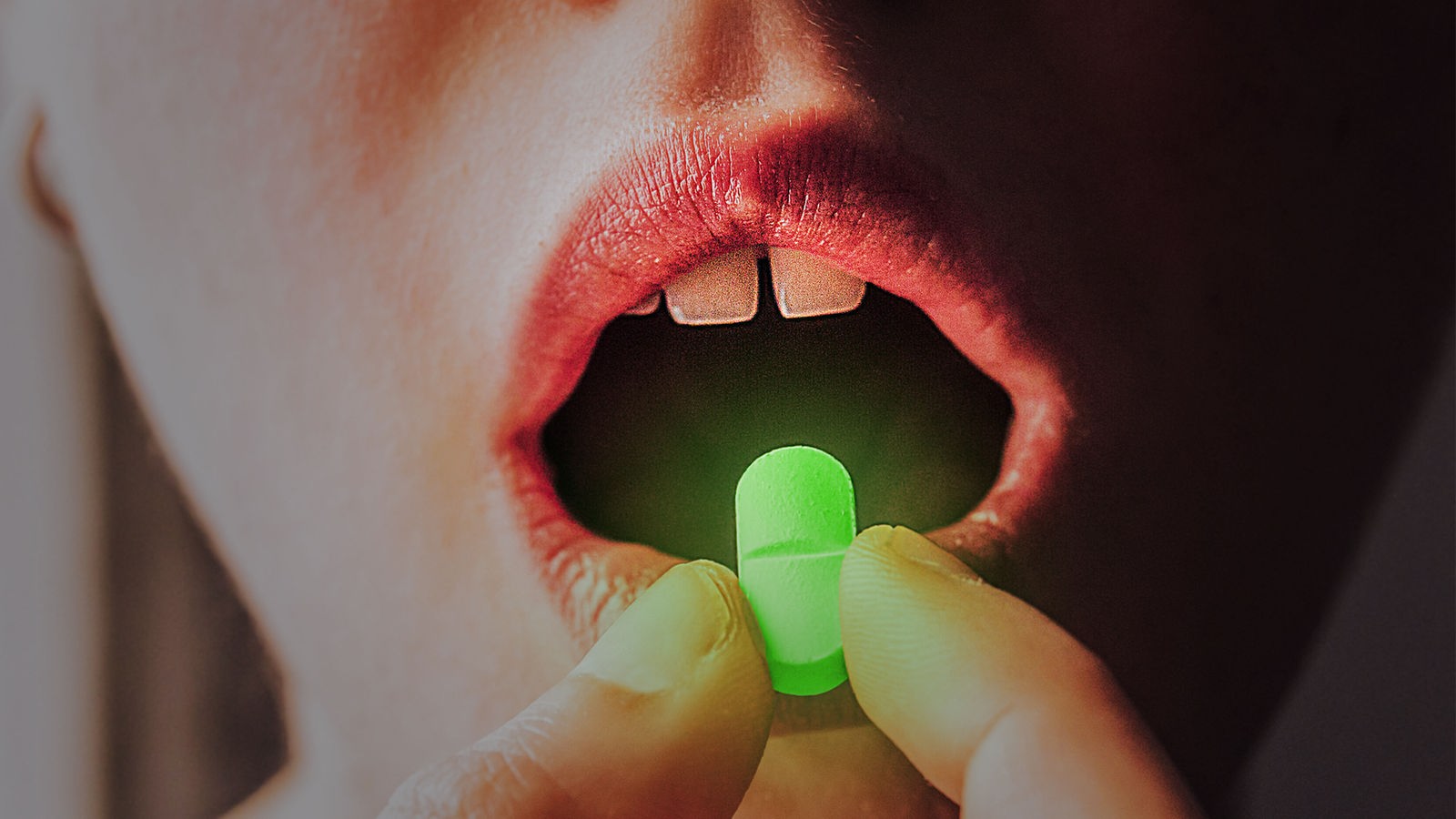 Eine leuchtende Pille wird vor einen Mund gehalten. 