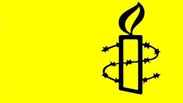 Das Logo von Amnesty International: Eine leuchtende Kerze von Stacheldraht umrandet vor grell gelbem Hintergrund.