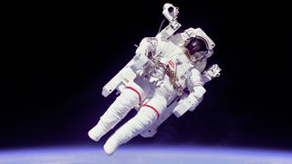 Ein Astronaut schwebt im Weltall, hinter ihm die blaue Erde und der schwarze Himmel.
