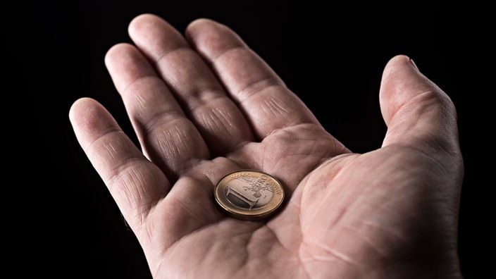 Hand eines älteren Mannes mit einer Ein Euromünze