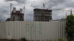 Blick auf einen Zaun mit dem Schriftzug "Game Over" vom Armenviertel Vila Autódromo aus auf den Olympiapark