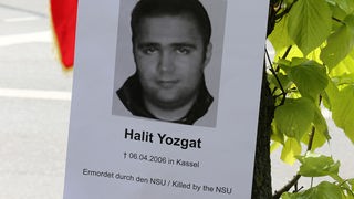  Ein Foto des NSU-Opfers Halit Yozgat hängt an einem Baum vor dem Oberlandesgericht München.