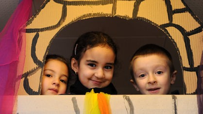 Rania (l-r), Sara und Leon schauen am Donnerstag (19.01.2012) in der katholischen Kindertagesstätte St. Joseph in Kassel vom selbst gebastelten Rapunzelturm hinaus