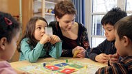 Test-Begleiterin Eva Briedigkeit spielt mit vierjährigen Kindergartenkindern in Düsseldorf den Sprachtest Delfin