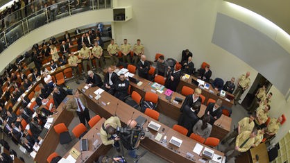 Die Angeklagte Beate Zschäpe (graues Sakko) steht am 14.05.2013 im Gerichtssaal in München (Bayern) mit ihren Anwälten zusammen hinter der Anklagebank