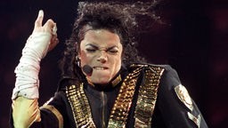 Michael Jackson beißt sich mit zugekniffenen Augen auf die Lippe.