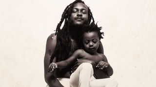 Cover des Albums "Strength" von Samory I: Mann mit freiem Oberkörper und geschlossenen Augen hält Kind auf seinem Schoß