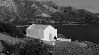 Cover des Albums "Insomnia" von Trettmann: Bild in Schwarz-weiss; Trettmann sitzt vor einem weiß gekalktem Gebäude; im Hintergrund ein Küstenstreifen