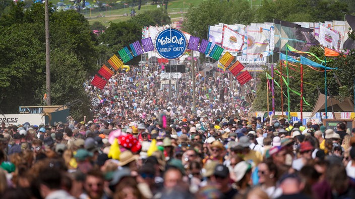 Festivalbesucher gehen unter einem Torbogen mit der Aufschrift «Vote Out to Help Out» während des Glastonbury Festivals.