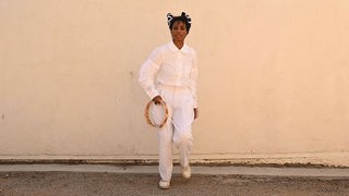 Santigold: "Shake" - die Sängerin, ganz in weiß gekleidet mit einem Tambourin in der Hand vor einer Wand stehend. 