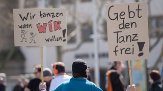 Ein Teilnehmer einer Versammlung gegen das Tanzverbot hält am 03.04.2015 in Stuttgart (Baden-Württemberg) Schilder mit der Aufschrift "Wir tanzen wann wir wollen!" und "Gebt den Tanz frei". (Archivfoto)