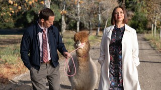 Miliardärin Molly (Maya Rudolph) geht mit Buchhalter Arthur (Nat Faxon), der ein Lama an der Leine führt, im Park spazieren