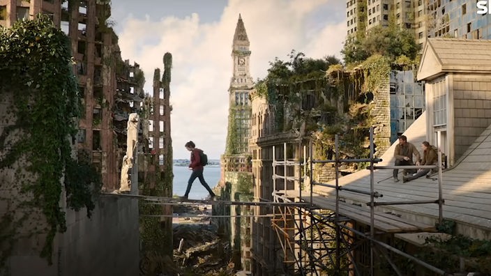 "The Last of Us" -  Die Hauptdarstellerin geht in luftiger Höhe über eine Planke zwischen zwei zerstörten Häusern.  