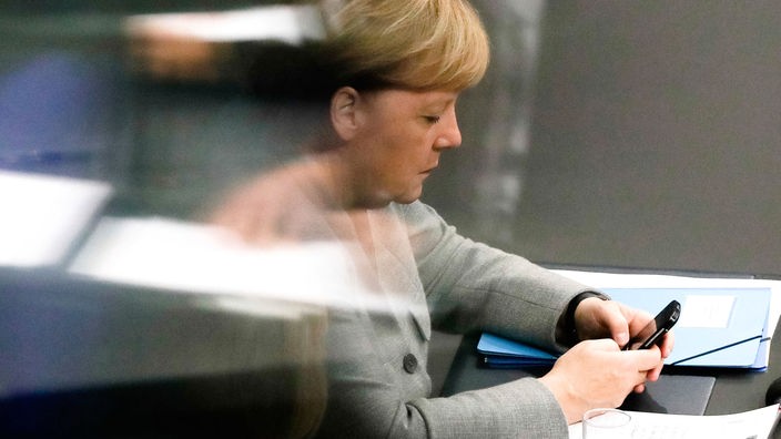 Angela Merkel guckt auf ihr Handy im Bundestag