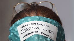 Eine Demonstrantin trägt eine Maske mit dem Schriftzug "Wahrheitssuche - Corona Lüge - Informiert euch!!!"