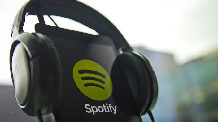 Spotify Logo na displeju mobilnog telefona sa slušalicama