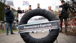 In Hamburg lebende Journalistinnen und Journalisten aus der Türkei stehen mit einem schwarzen Kranz vor dem Türkischen Konsulat. 