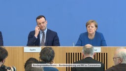 Jens Spahn und Angela Merkel sitzten nebeneinander bei der Pressekonferenz