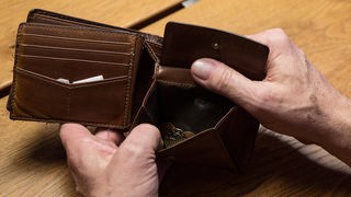 Symbolbild: Ein Mensch hält eine nahezu leere Geldbörse in den Händen.