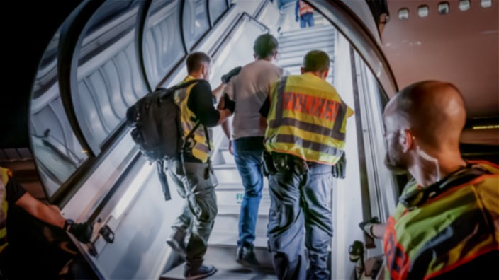 Ein Flüchtling wird zur Abschiebung in ein Flugzeug gebracht