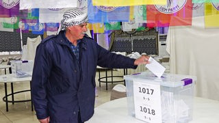 Ein mann wirft einen Wahlzettel in die Wahlurne