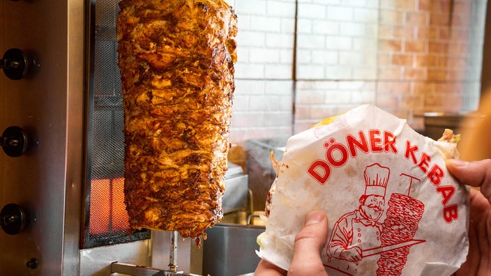 Döner Kebab und ein saftiger, mit Fleisch bestückter Dönerspieß, Symbolbild für das beliebte Fastfood in Deutschland. FOTOMONTAGE