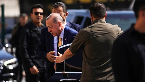 Der türkische Staatspräsident und Vorsitzende der AKP-Partei, Recep Tayyip Erdogan, Mitte, kommt zur Stimmabgabe für die Kommunalwahlen in ein Wahllokal. 